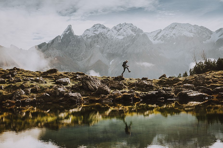 Wanderer an Bergsee mit Bergen im Hintergrund
